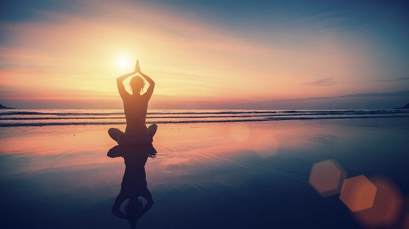 Silhouette meditation girl on the background of the sea and sunset. Yoga and healthy lifestyle.